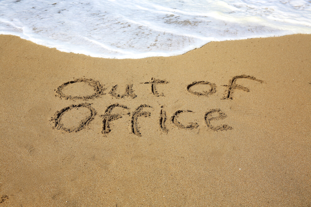 Out of office, a message written in the sand at the beach.
