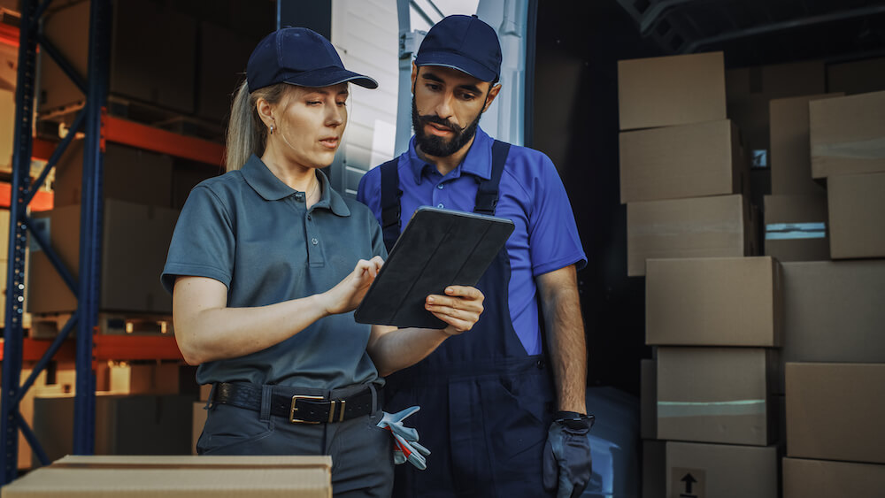 Outside of Logistics Distributions Warehouse With Inventory Manager Using Tablet Computer, talking to Worker Loading Delivery Truck with Cardboard Boxes. Online Orders, Purchases, E-Commerce Goods